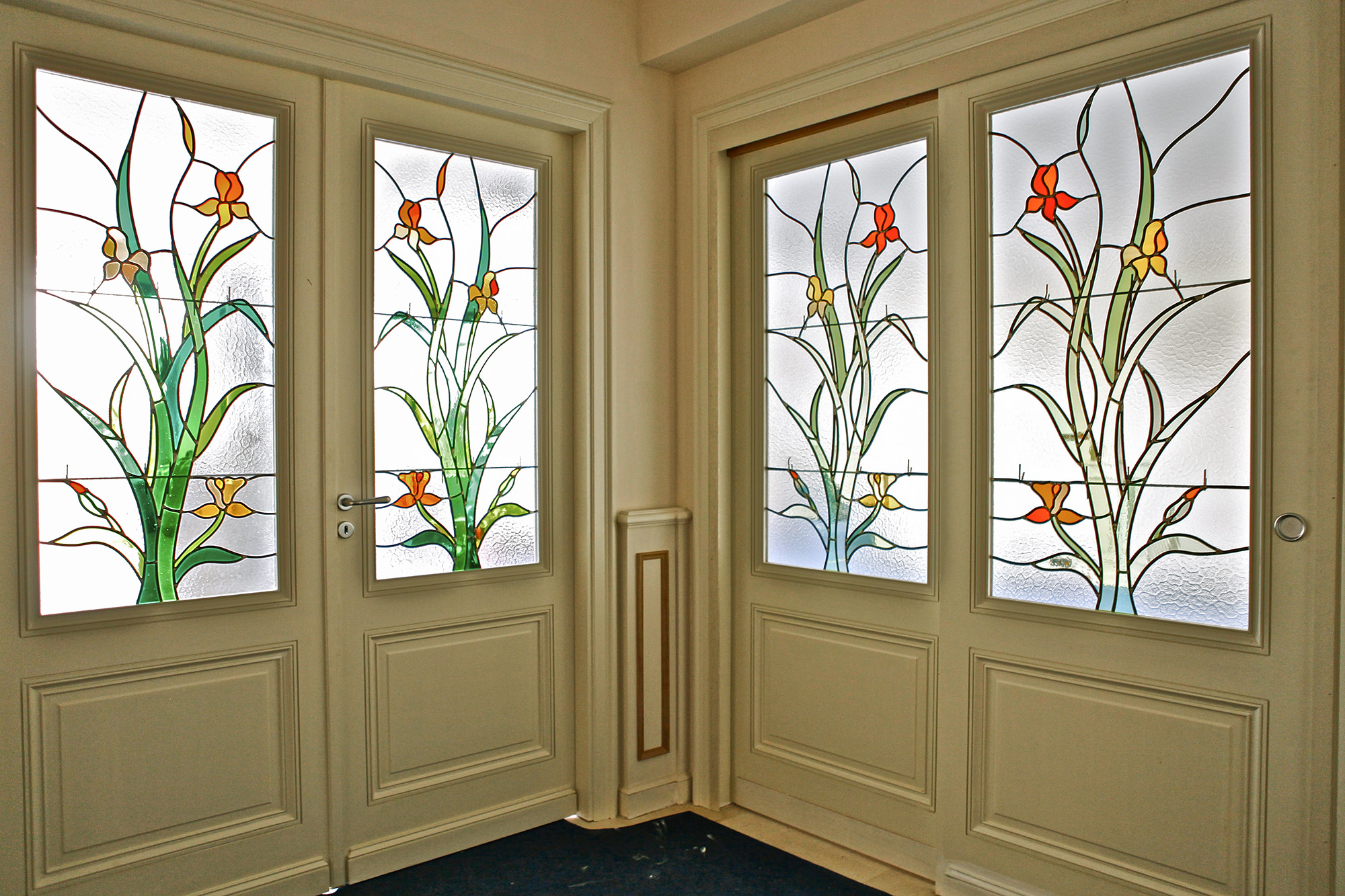 vitraux au motif floral posé sur deux portes intérieures dans un hall d'entrée en décor de maison chez un particulier, réalisé par l'Atelier Vitrail Saint-Joseph